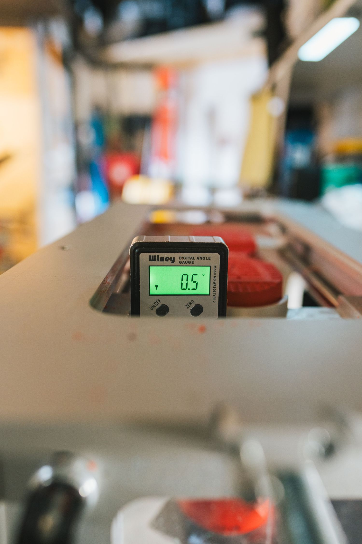 Winey digital angle gauge displaying 0.5 degrees on a green LCD screen mounted on workshop equipment.