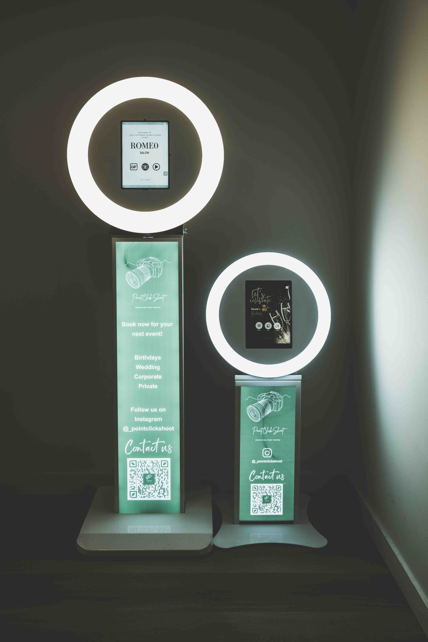 Modern photo booth display with circular ring lights and digital screens showing QR codes and menu options.