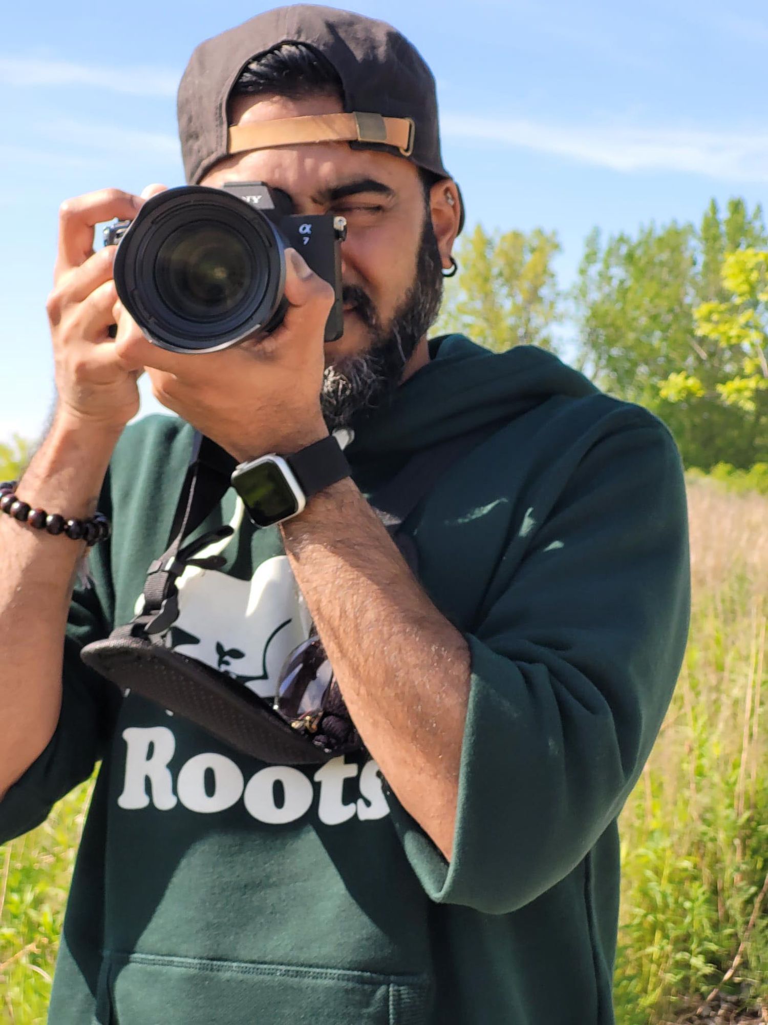 Photographer taking pictures outdoors wearing dark hoodie.