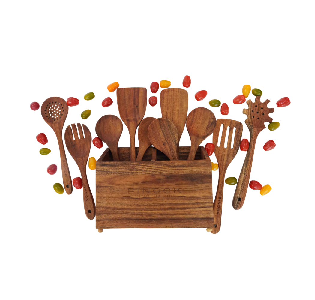Set of wooden kitchen utensils including spoons and spatulas displayed in a square wooden holder with colorful candy.