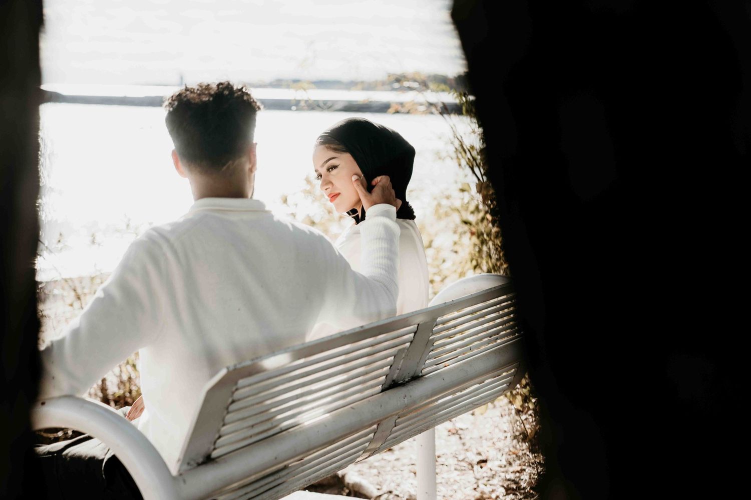 A romantic moment captured in silhouette against a bright background on a bench.