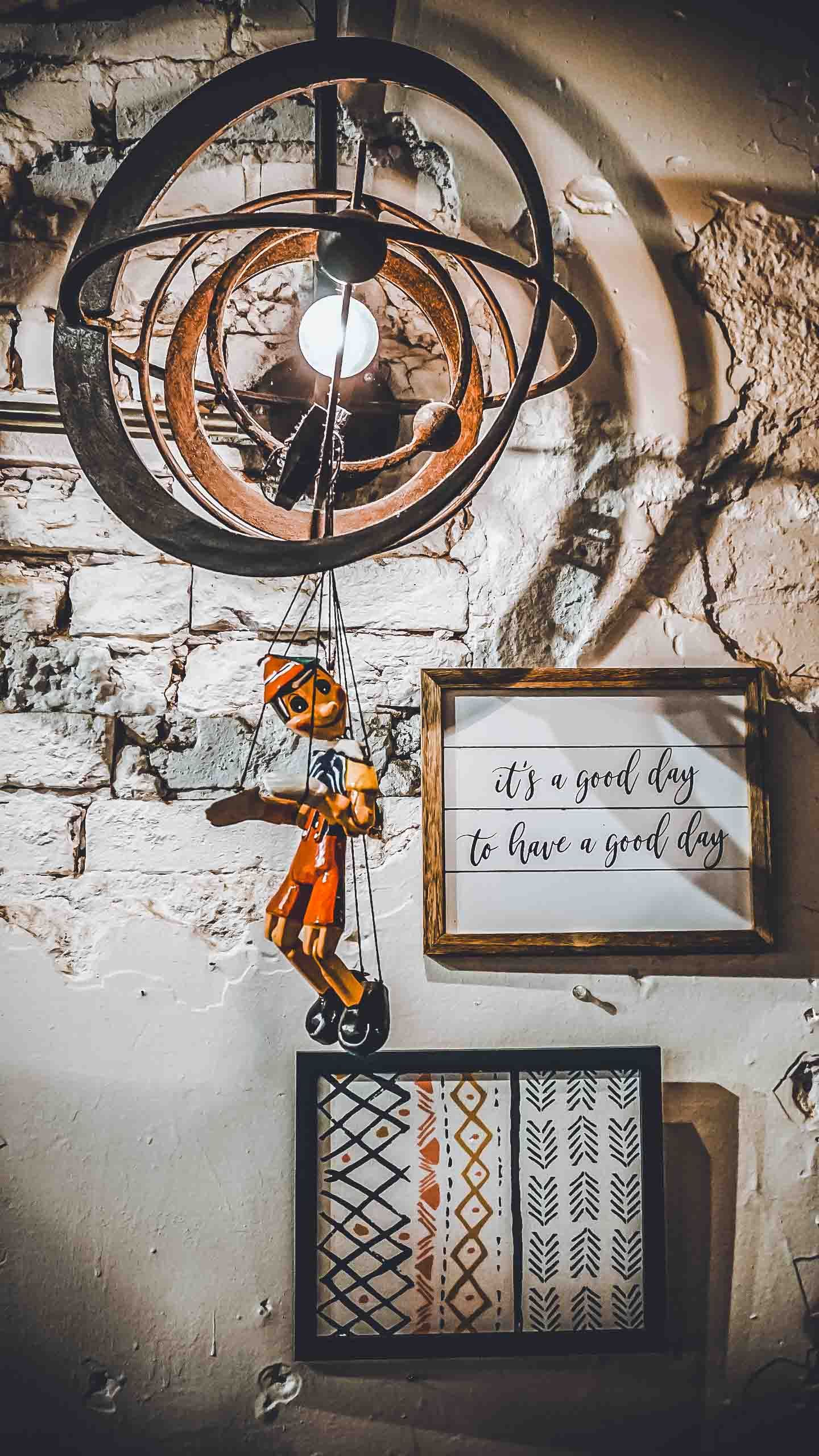 Rustic industrial light fixture and framed wall art with text 'it's a good day' against exposed brick wall.