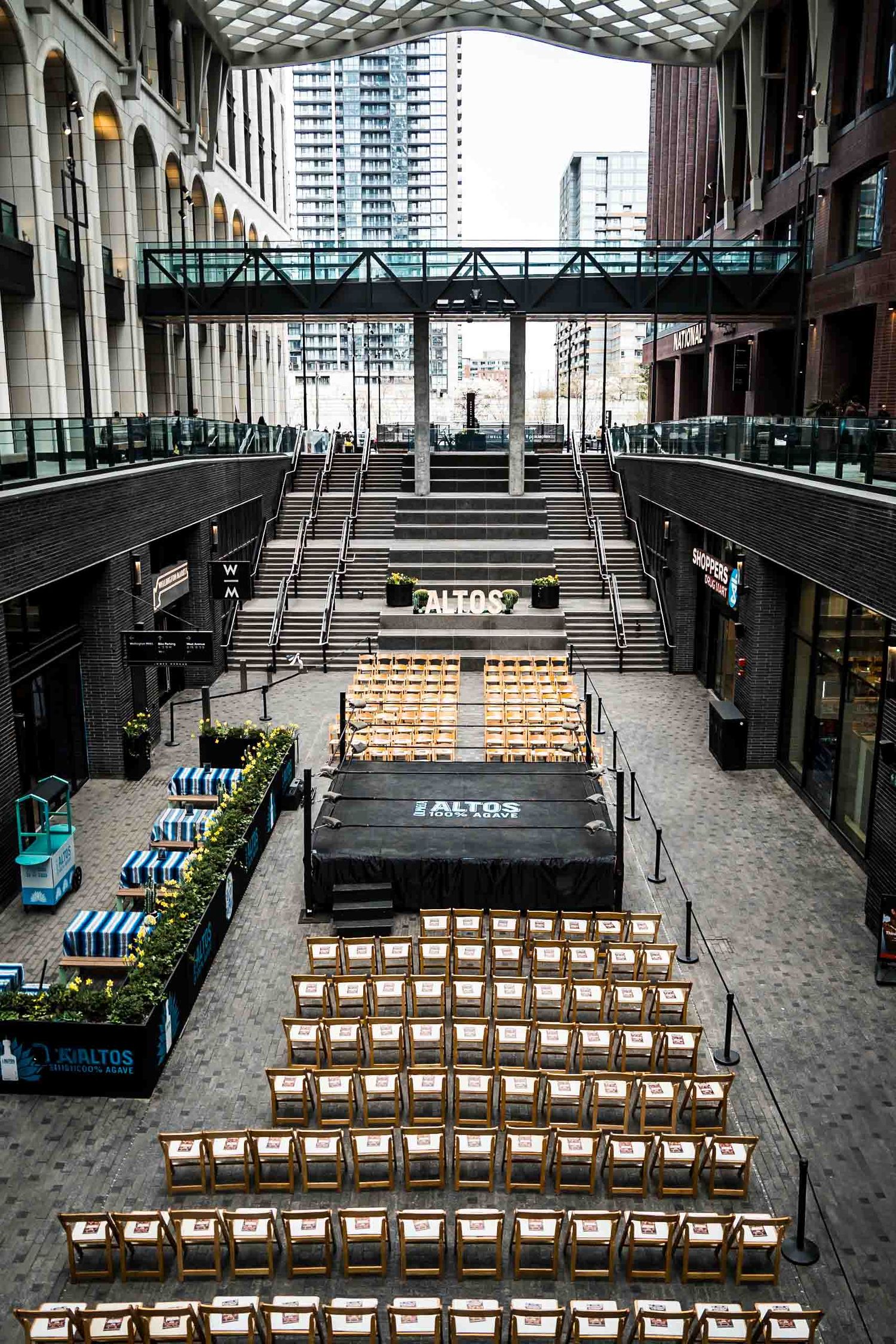 Overhead view of an event space with rows of wooden chairs facing black stage platform.