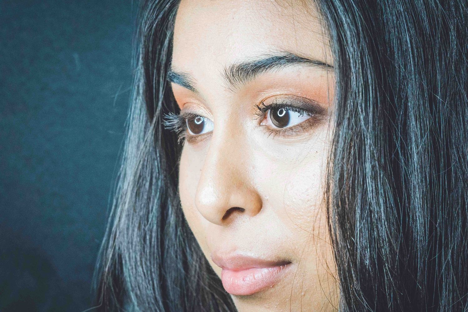 Close-up beauty portraits with dramatic lighting against dark background.