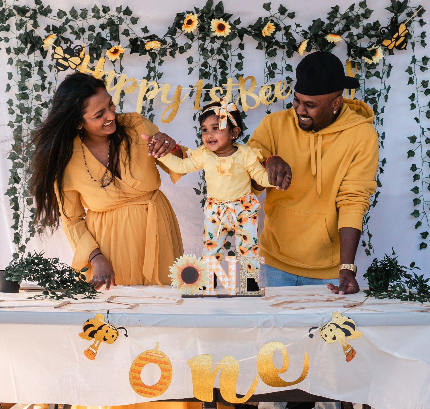 Family wearing matching yellow outfits poses together with black butterfly decorations in the background.
