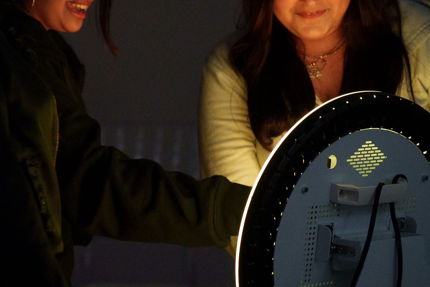 Interactive display screens illuminated by ring light in dark setting.