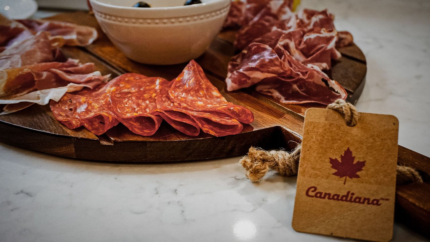 Artisanal charcuterie board with rustic brown paper labels for identifying meats and cheeses.