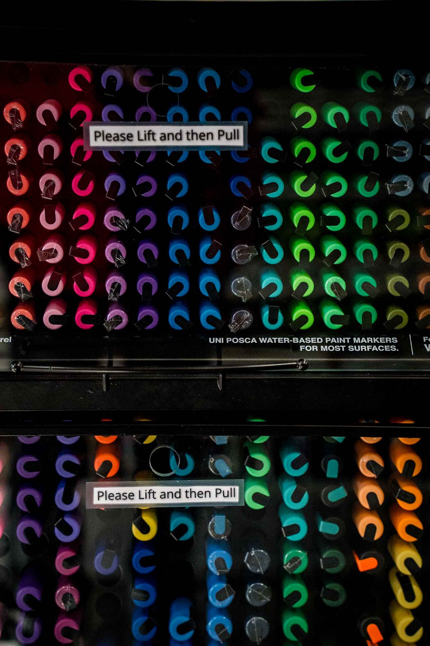 Colorful Uni Posca water-based paint markers displayed in a vending machine.