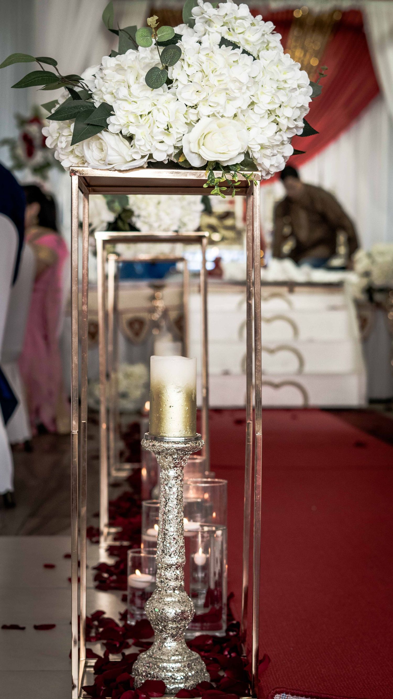 Elegant centerpiece featuring white hydrangeas in a tall glass vase with candle holders.
