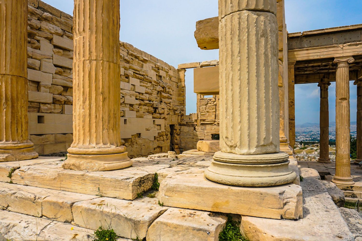 Ancient Greek ruins with Doric columns against blue sky at the Acropolis.