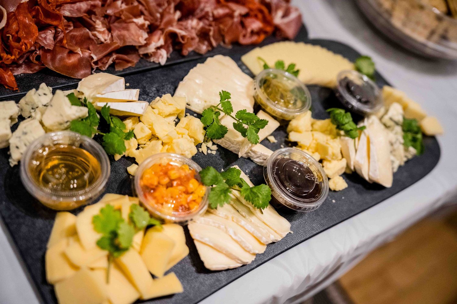 Assorted meats, cheeses and condiments displayed on dark serving plates.