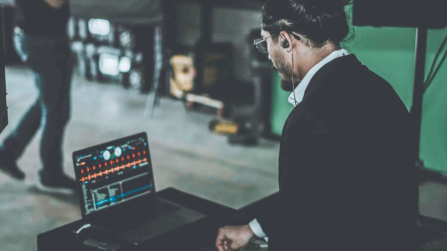 Music producer working on digital audio workstation in dimly lit studio.
