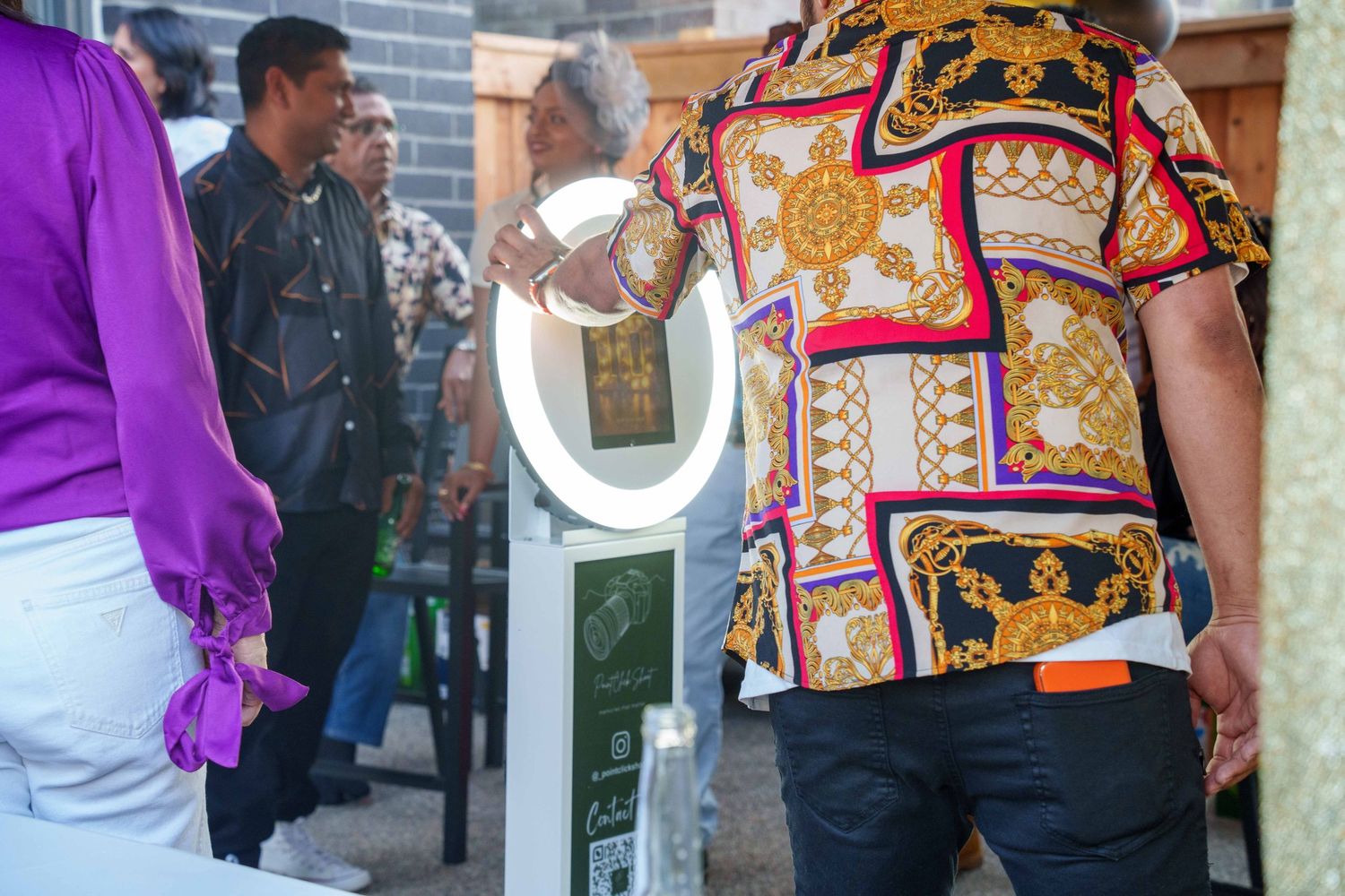 People gathered on a street wearing colorful patterned clothing and bright purple accents.
