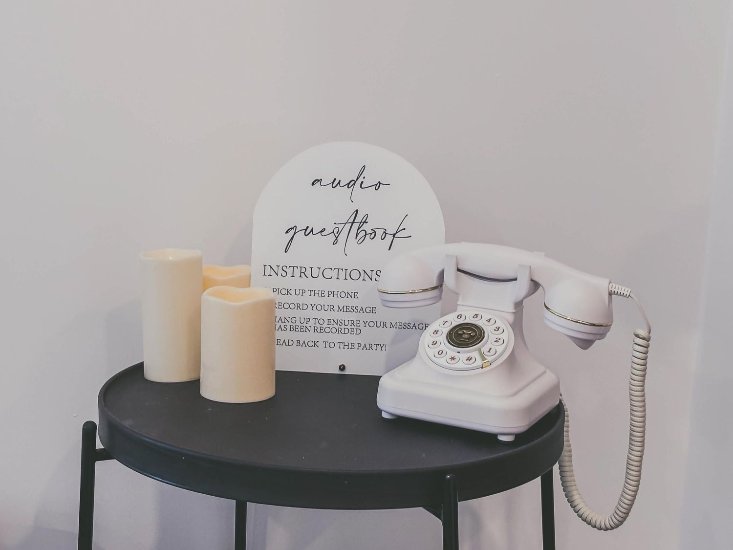 Minimalist display featuring retro telephone and instruction card on dark table.