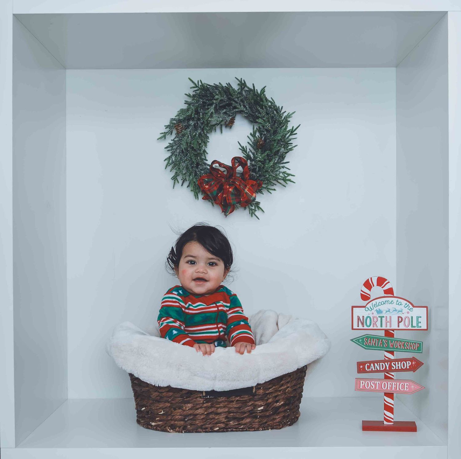 Holiday photography setup with festive decorations including candy cane signs and greenery.