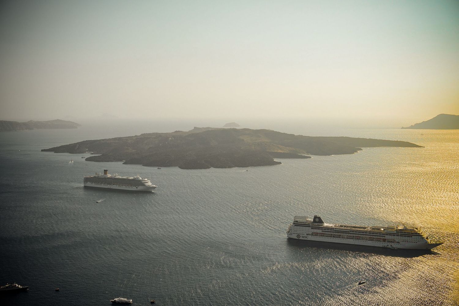 Scenic sunset view of Mediterranean islands with cruise ships sailing in the distance.