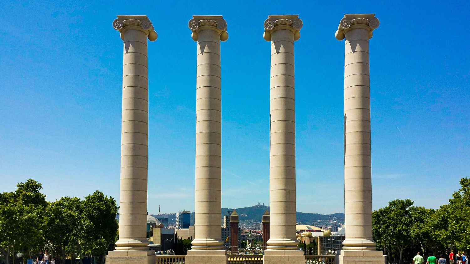 Row of classical white marble columns against bright blue sky in ancient Roman architecture.