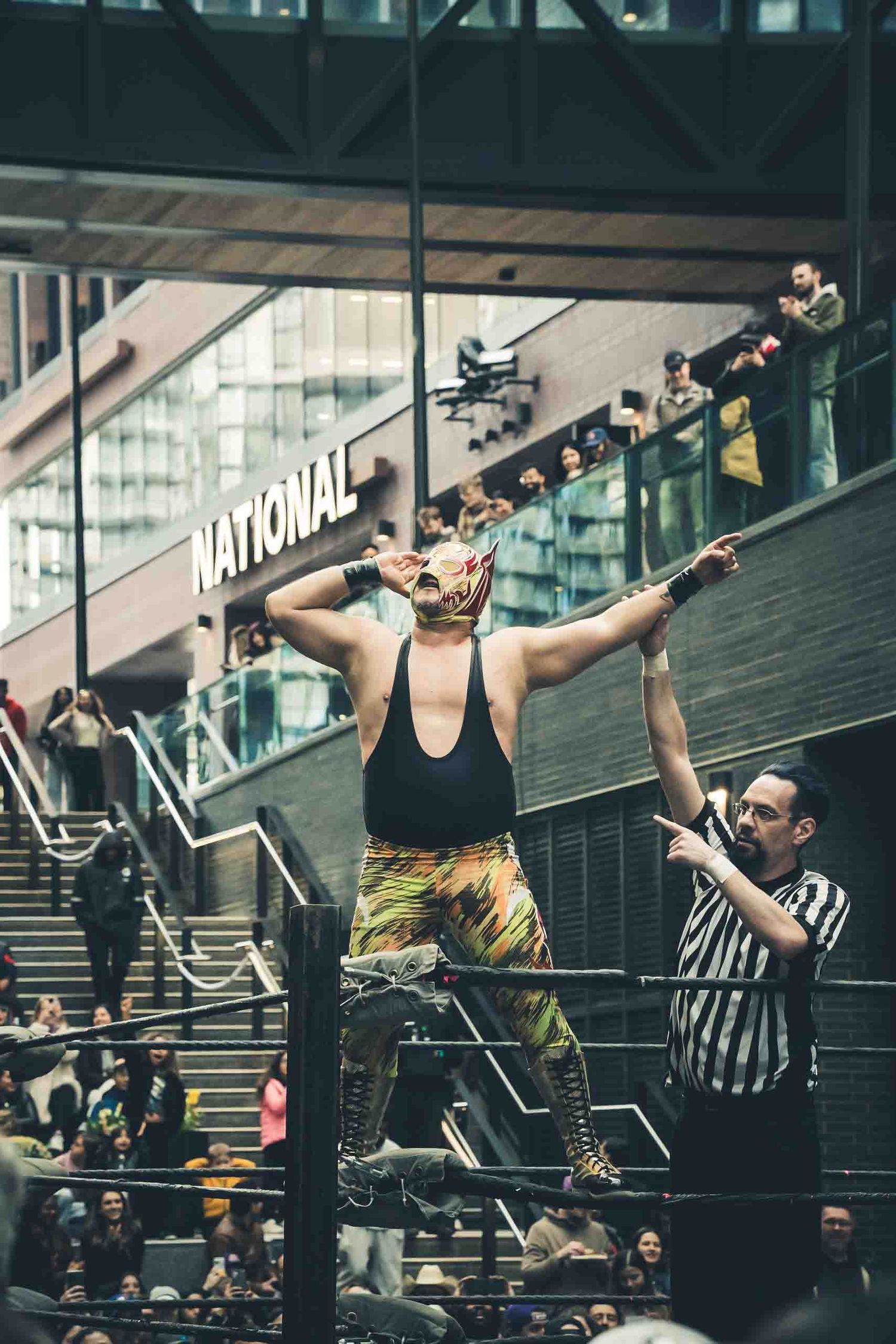 Professional wrestlers performing dramatic moves during match in indoor venue.