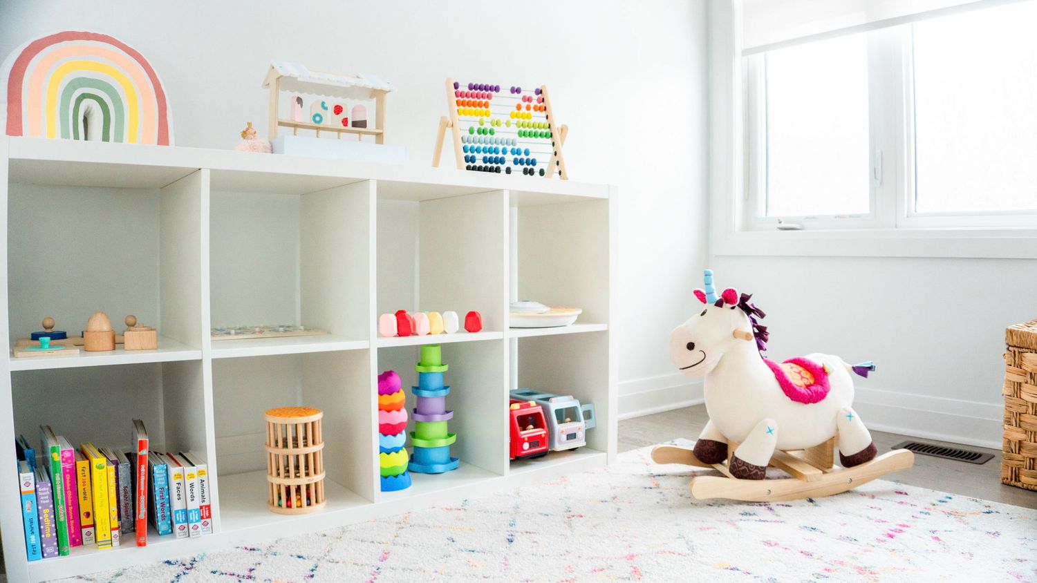Bright and organized playroom with white shelving units displaying colorful toys and books.