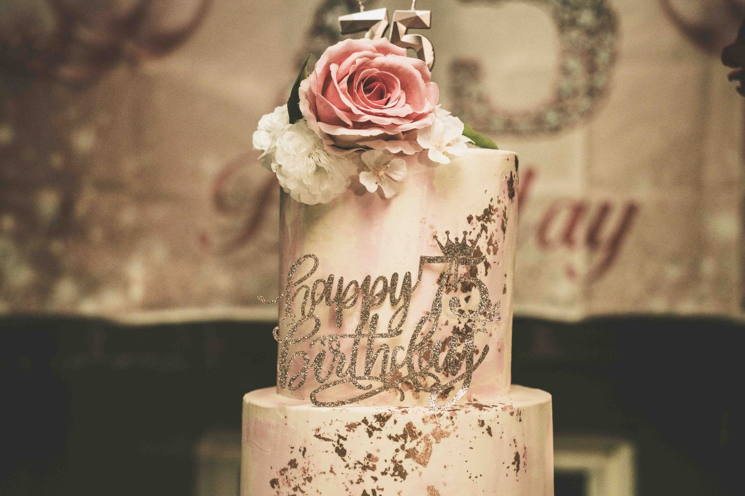 Elegant birthday cake featuring rose decorations and gold metallic details.