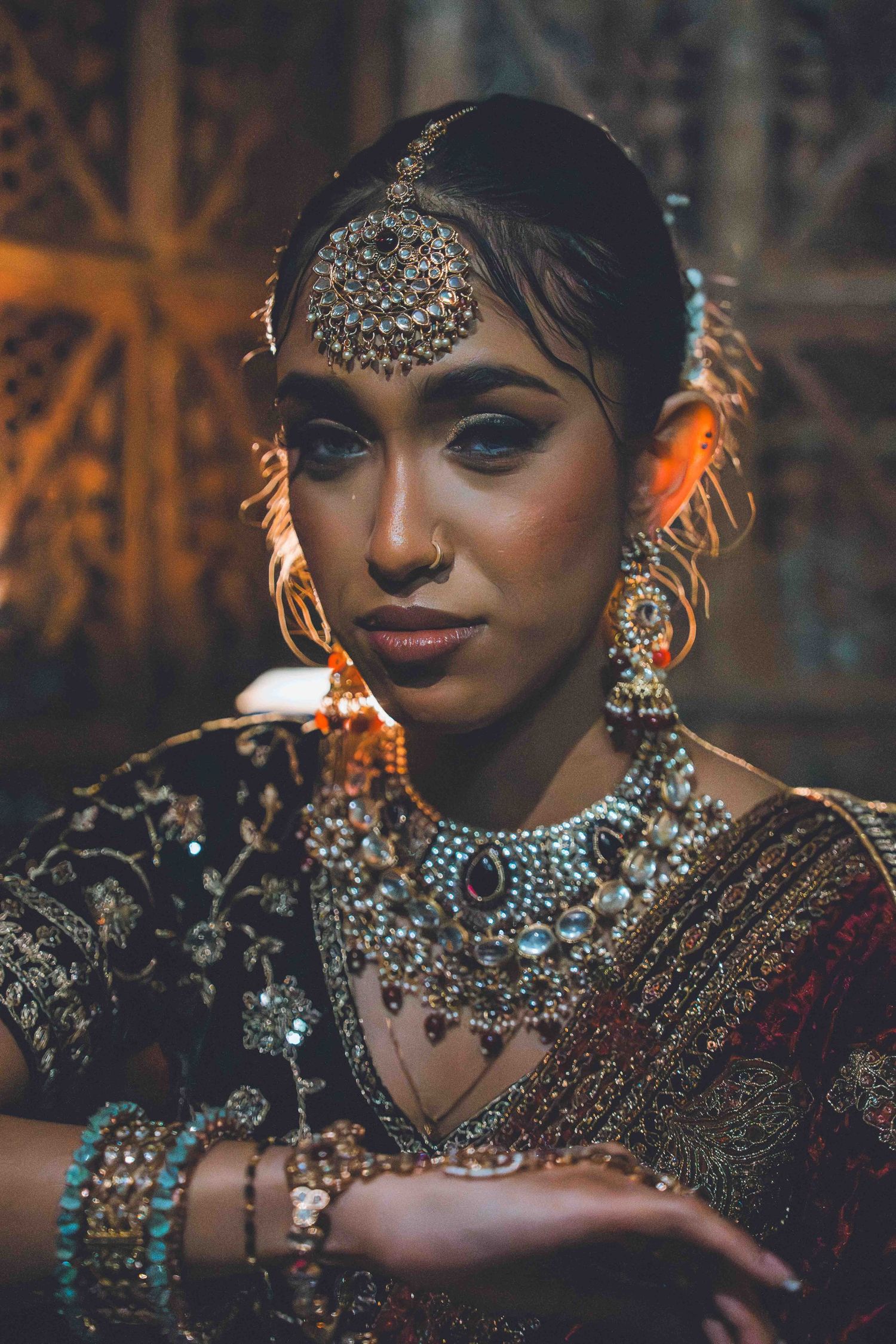Traditional South Asian bridal jewelry and attire featuring ornate crystal headpiece, statement necklace and earrings in warm lighting.