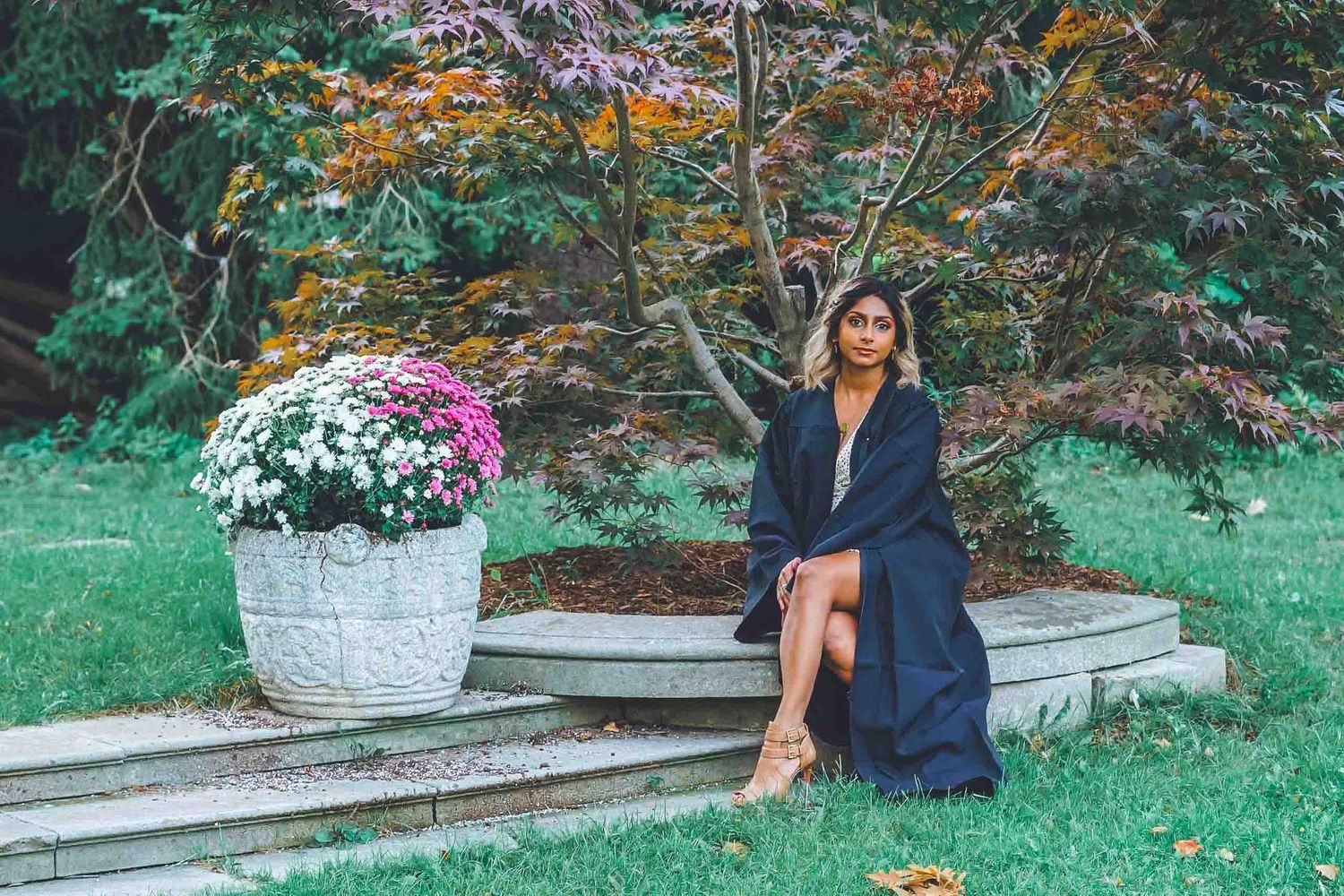 Graduation photo shoot in a garden setting with decorative stone pillars.