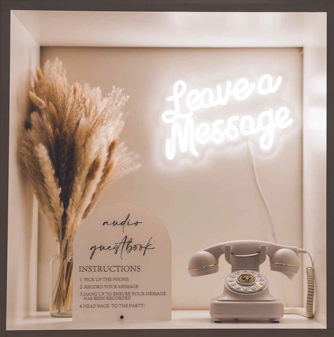 Vintage rotary phone display with neon sign and pampas grass decoration.