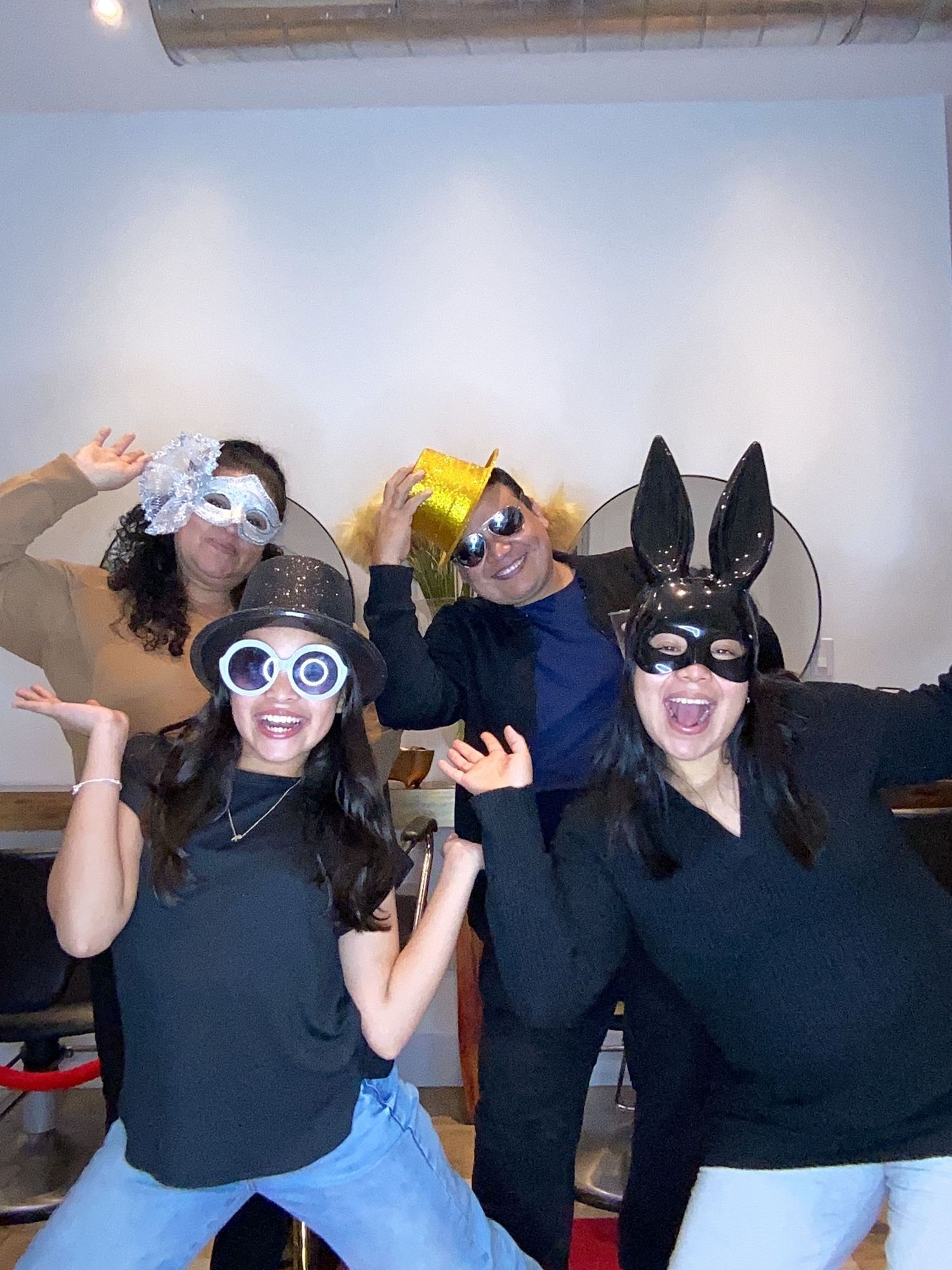 Group wearing fun masks and accessories pose energetically at a salon.