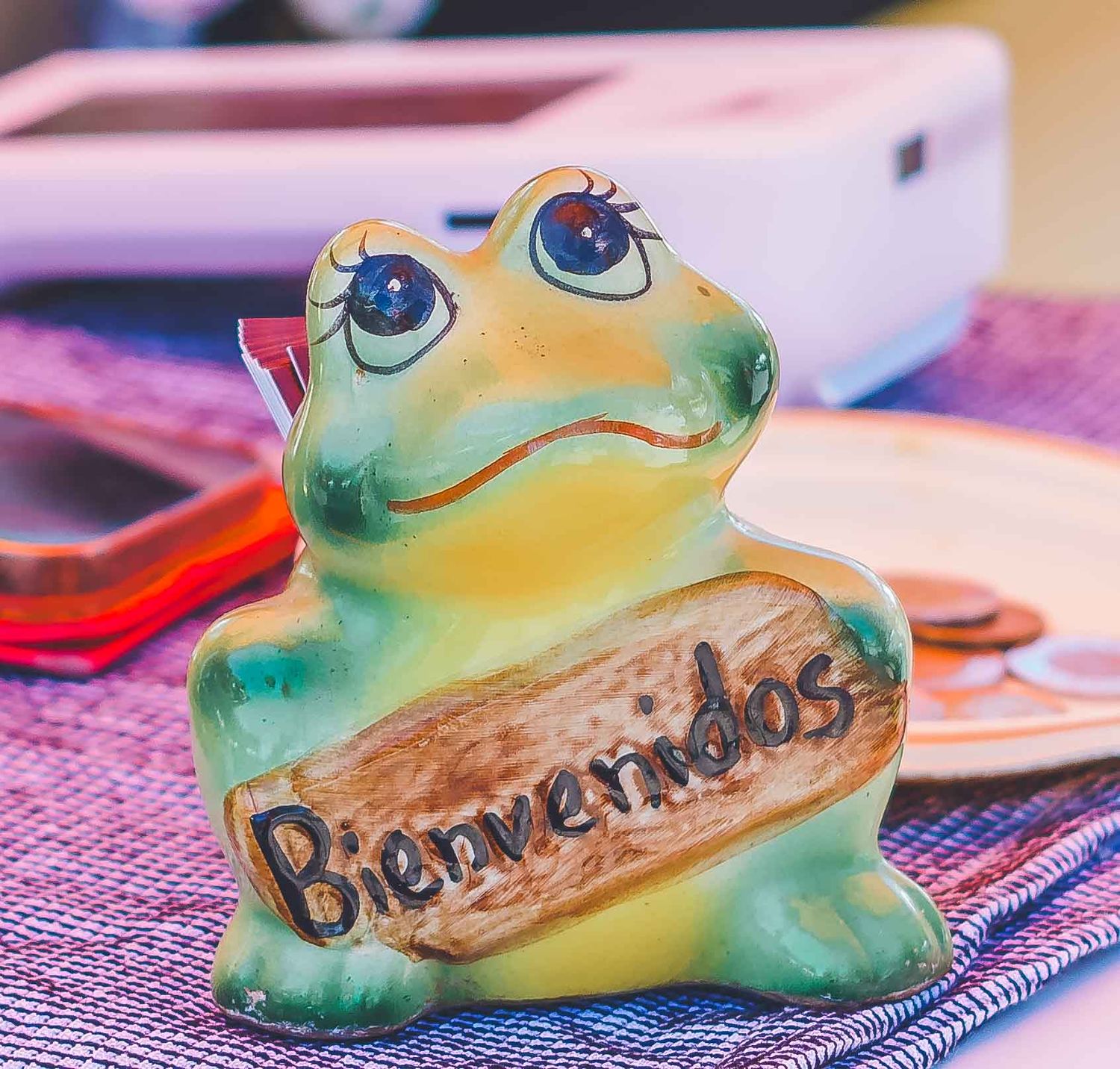 Decorative green frog-shaped cookie or cake with painted details on a purple placemat.