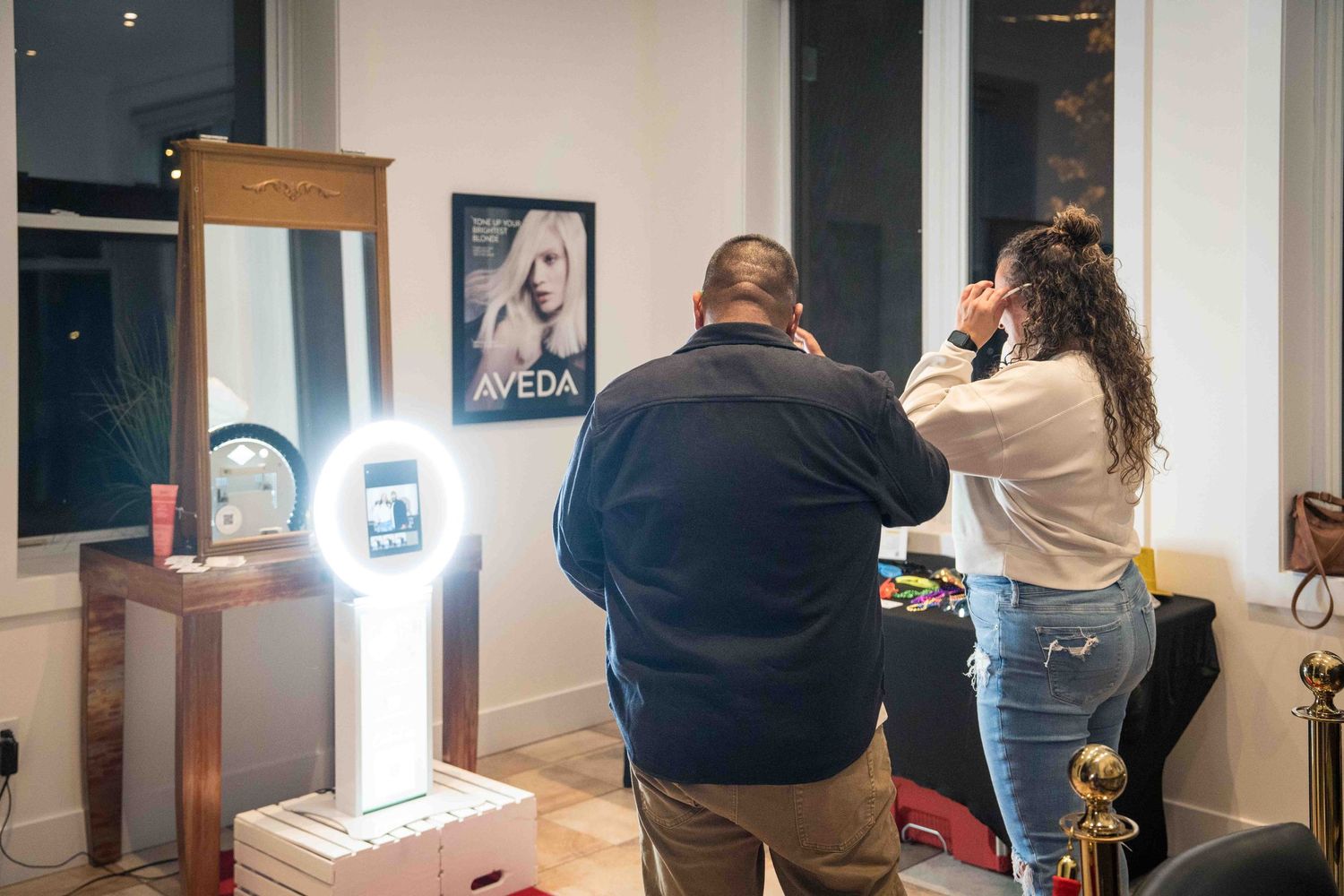 People using modern photo booth kiosk with ring light at indoor event.