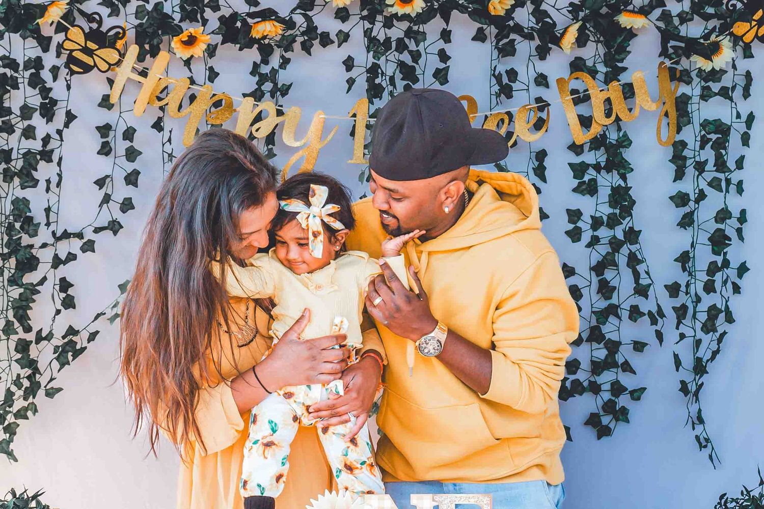 Family sharing joyful moment against floral backdrop with string lights.