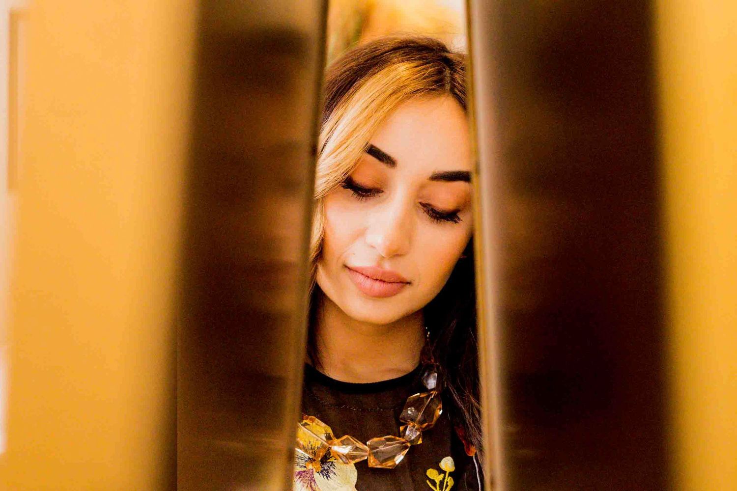 Warm-toned portrait in salon setting with golden lighting.