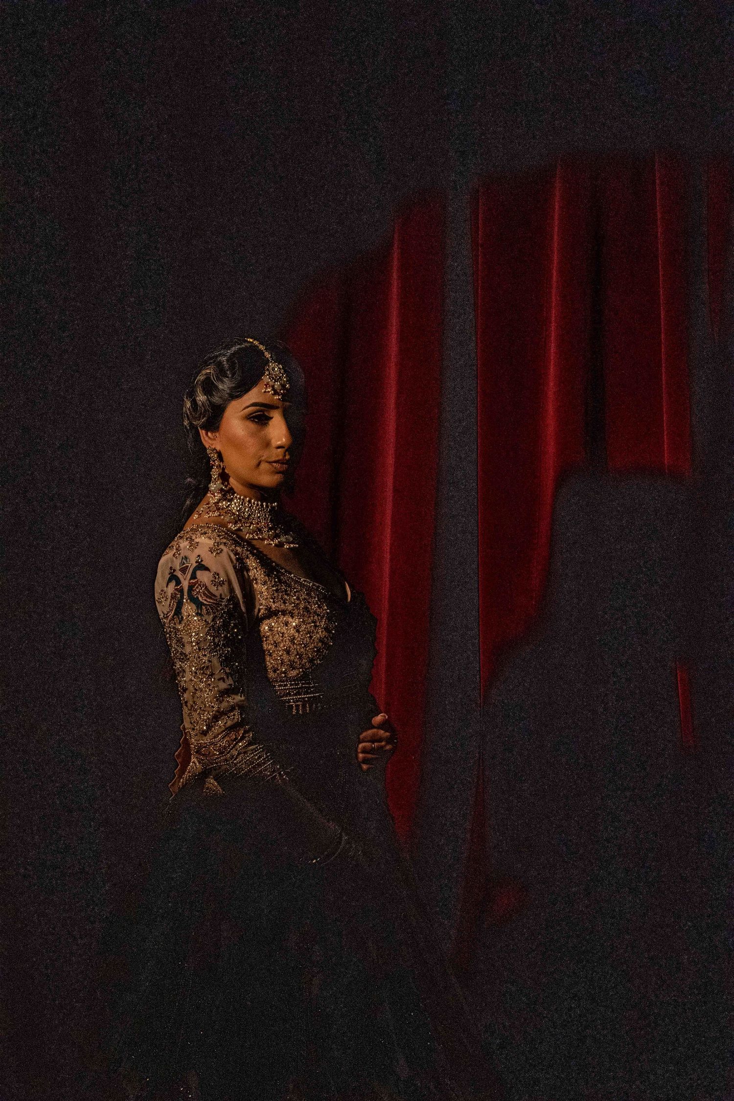 Dramatic portrait series against dark background with red curtain and leopard print outfit.