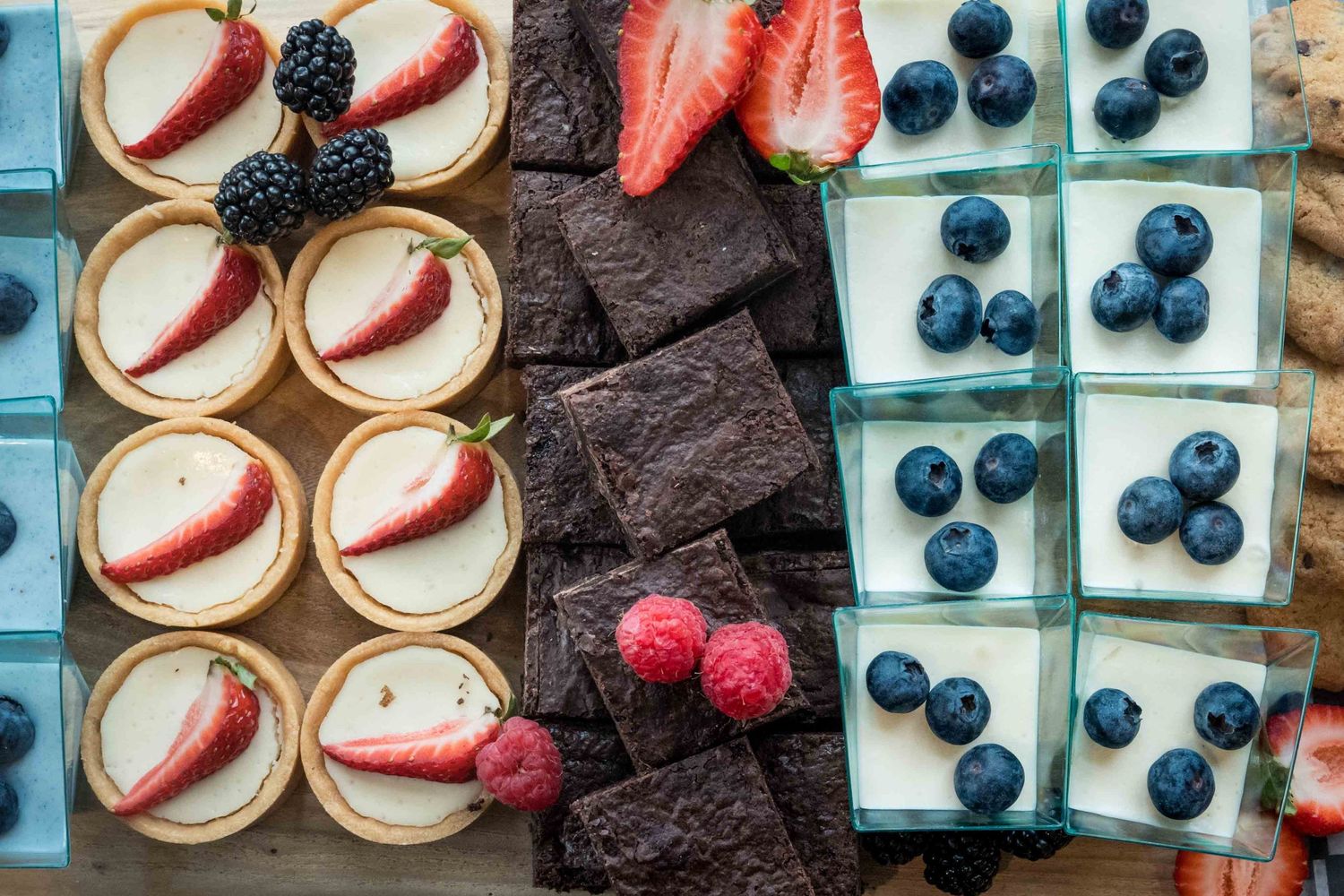 Assorted mini desserts with fresh strawberries, blueberries, blackberries, and raspberries on a platter.