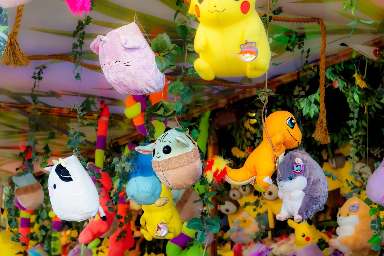 Colorful stuffed Pokemon plush toys hanging from ceiling at a carnival game booth or prize display.