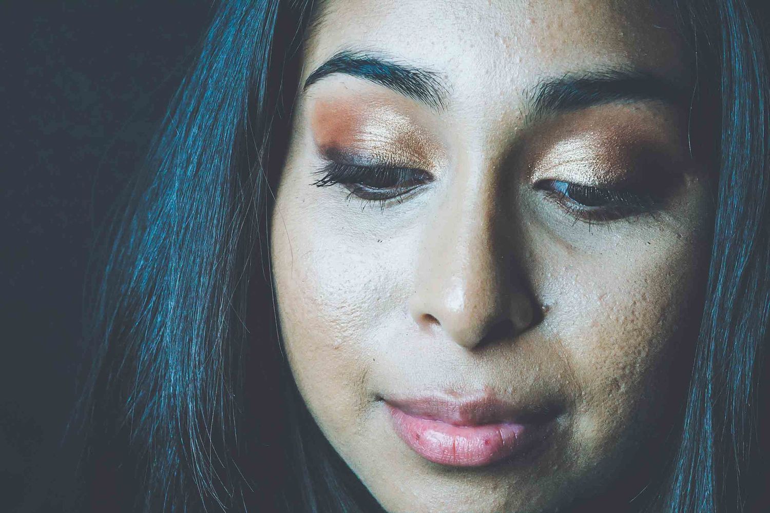 Close-up beauty portrait with dramatic lighting and shimmering eye makeup.