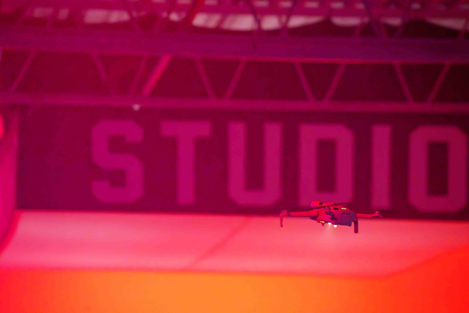 Silhouette of a drone captured against a dramatic pink-lit background.