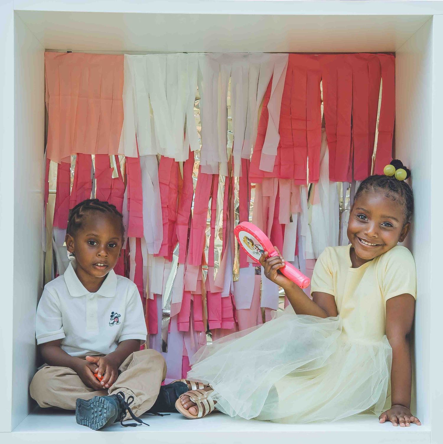Group photo in a white studio with pink and cream colored streamers in the background.
