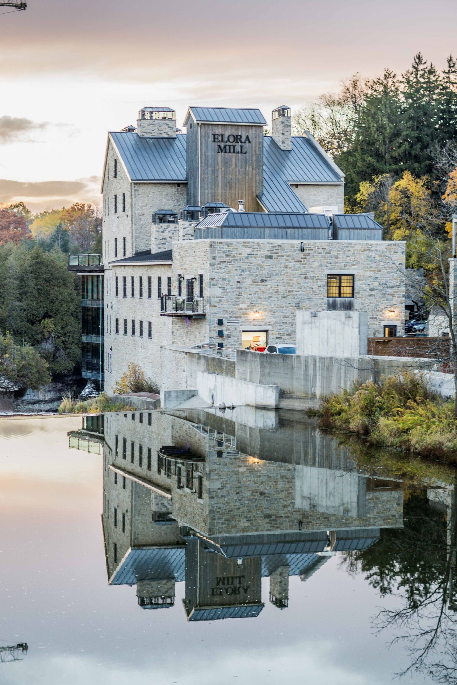 Perfect mirror reflection of Elora Mill Hotel in still water during golden hour.
