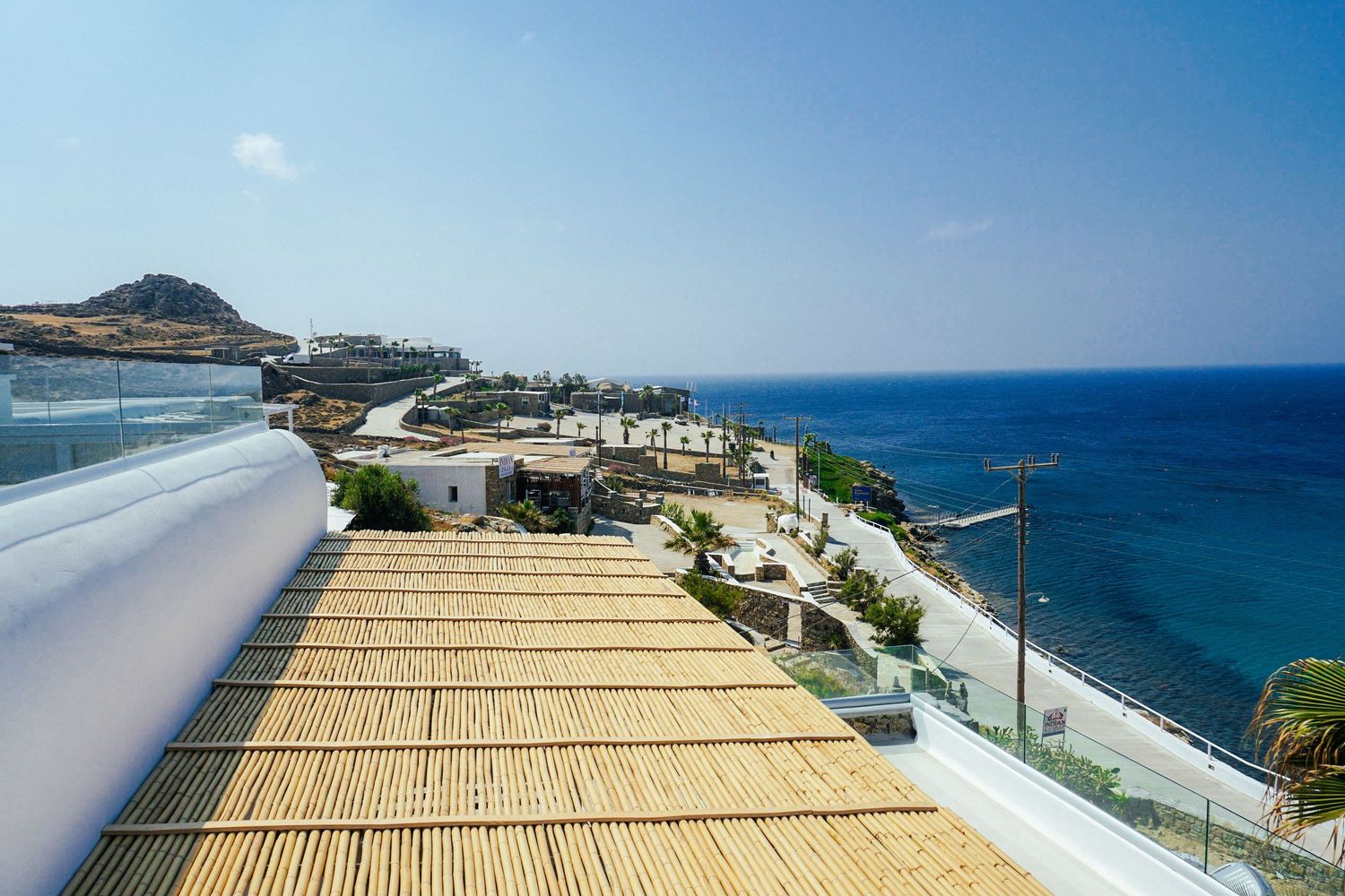 Seaside terrace with bamboo roof overlooking Mediterranean waters and coastal views.