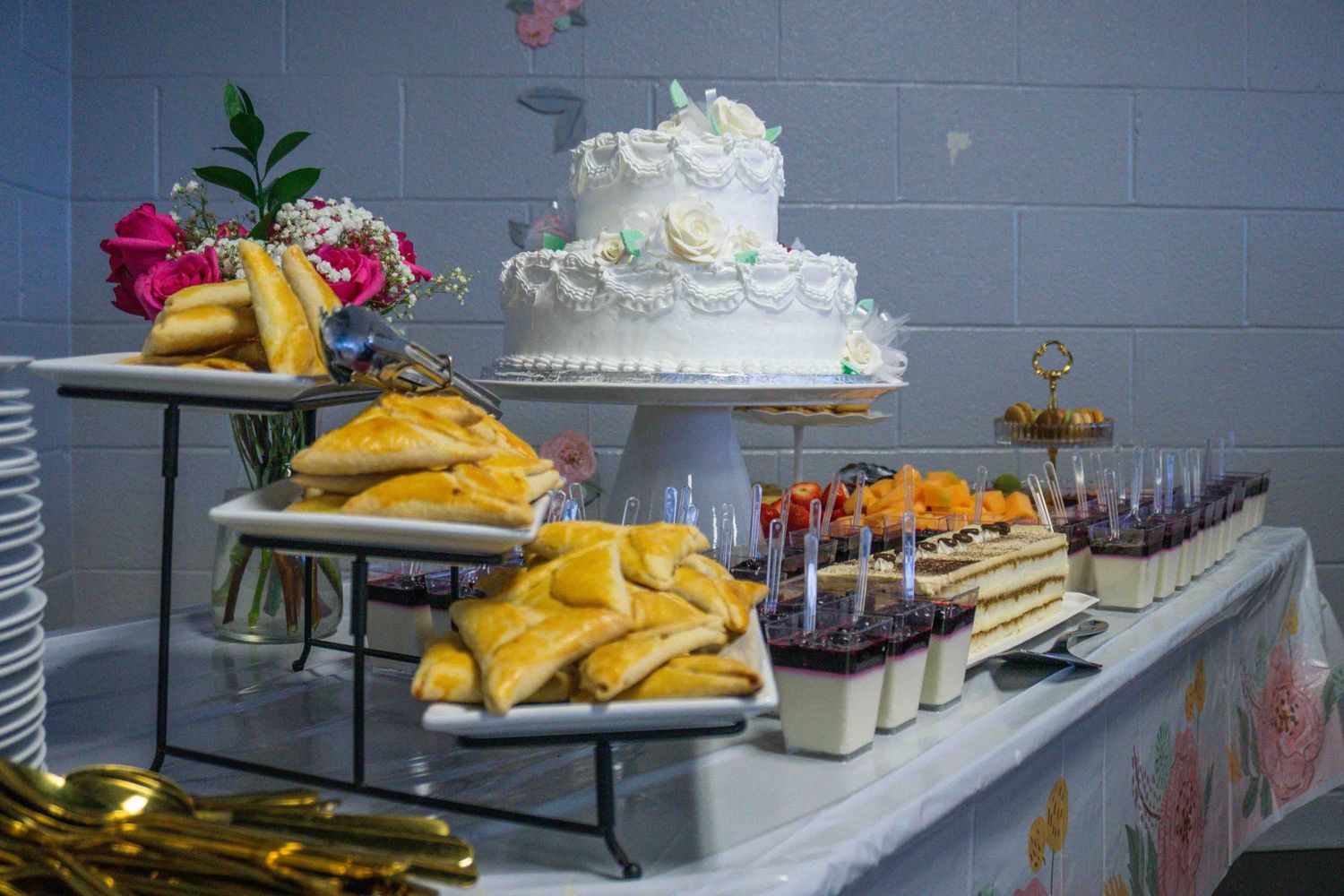 Wedding dessert table featuring a tiered white cake, fresh fruit and various sweet treats.