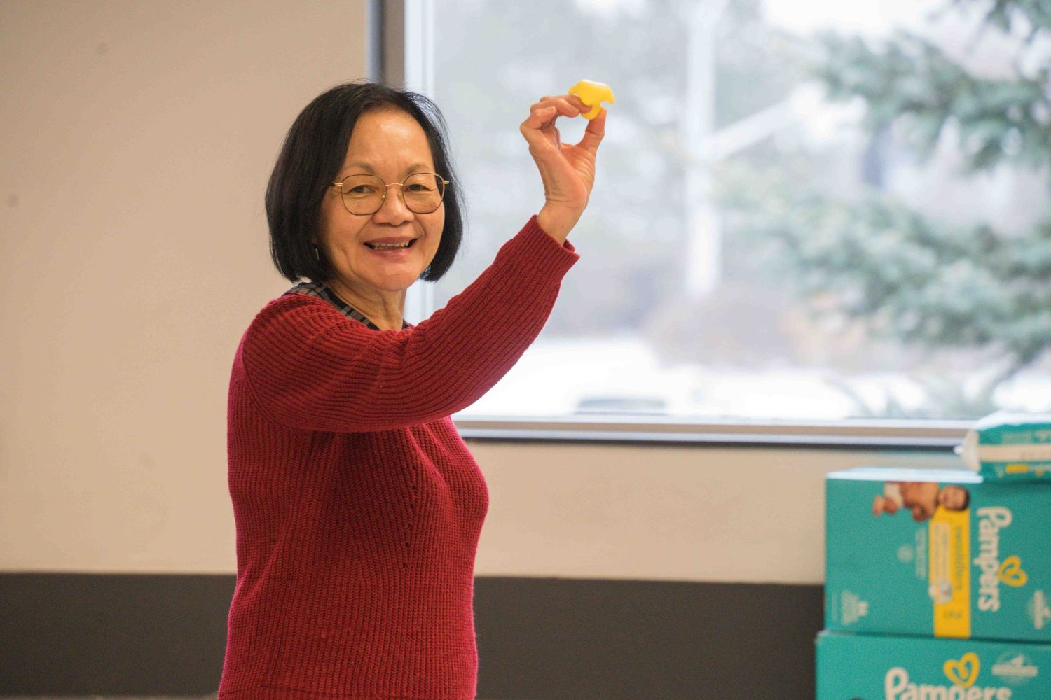 Person in red sweater making cheerful gestures near window.