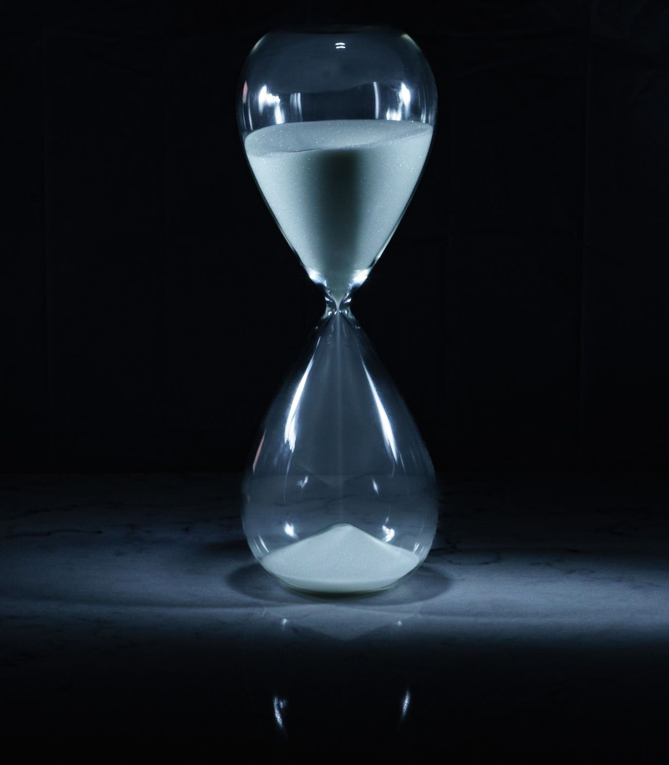 Series of hourglass photos showing sand flowing from top to bottom against dark background.