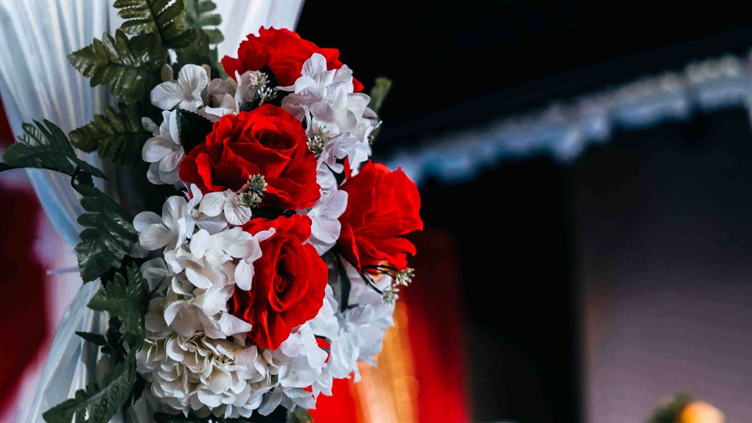 Red and white floral centerpieces with dramatic lighting at an elegant event.
