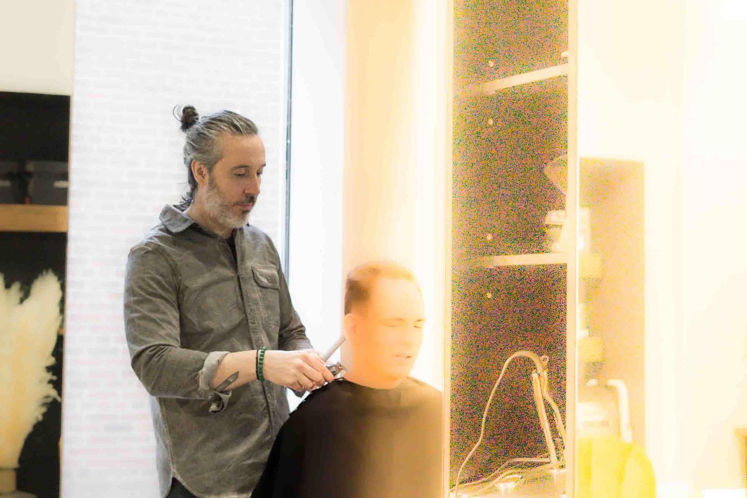 A professional stylist works with hair products in a bright modern salon space.