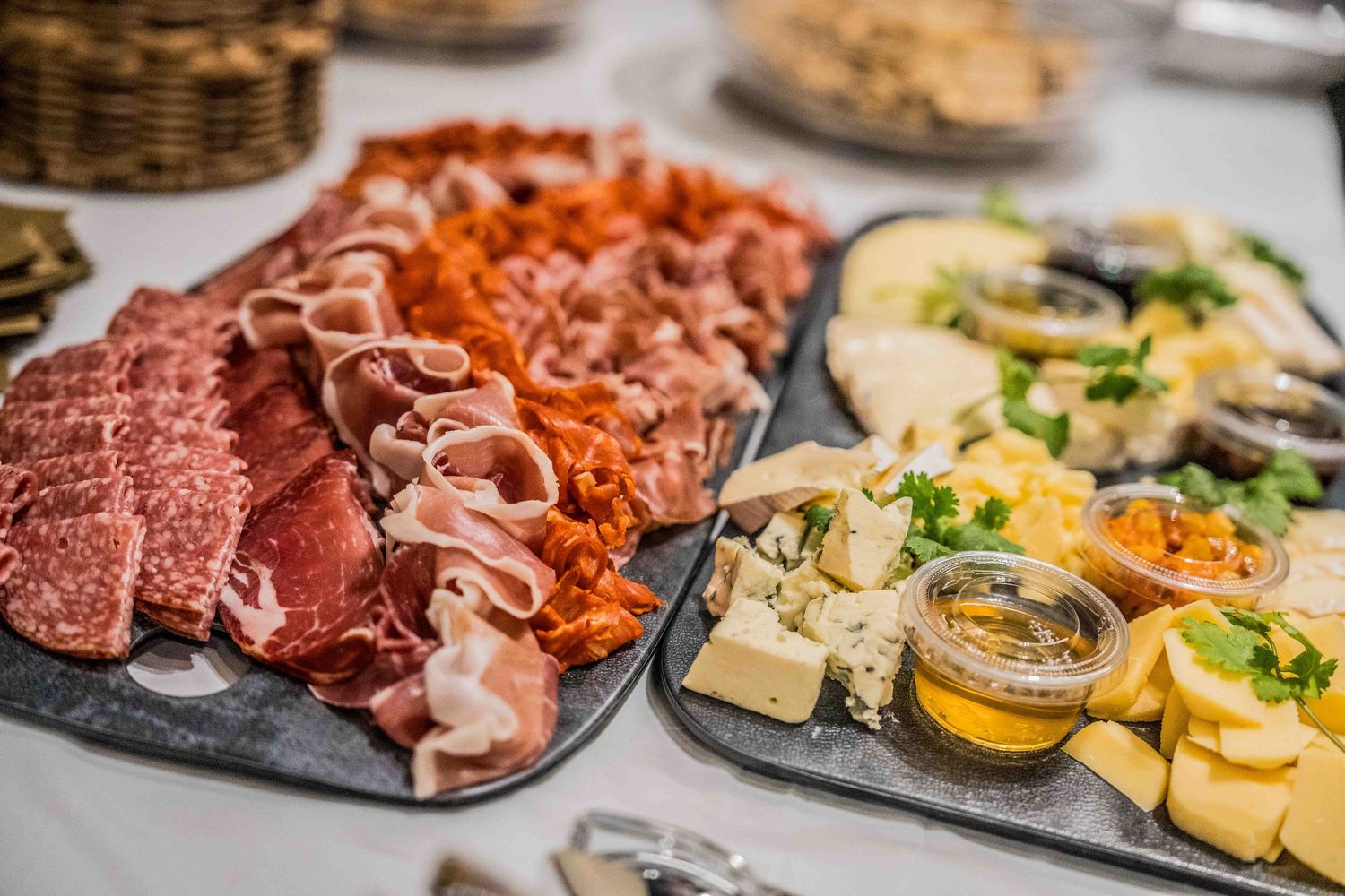 Multiple charcuterie boards arranged with meats, cheeses and accompaniments.