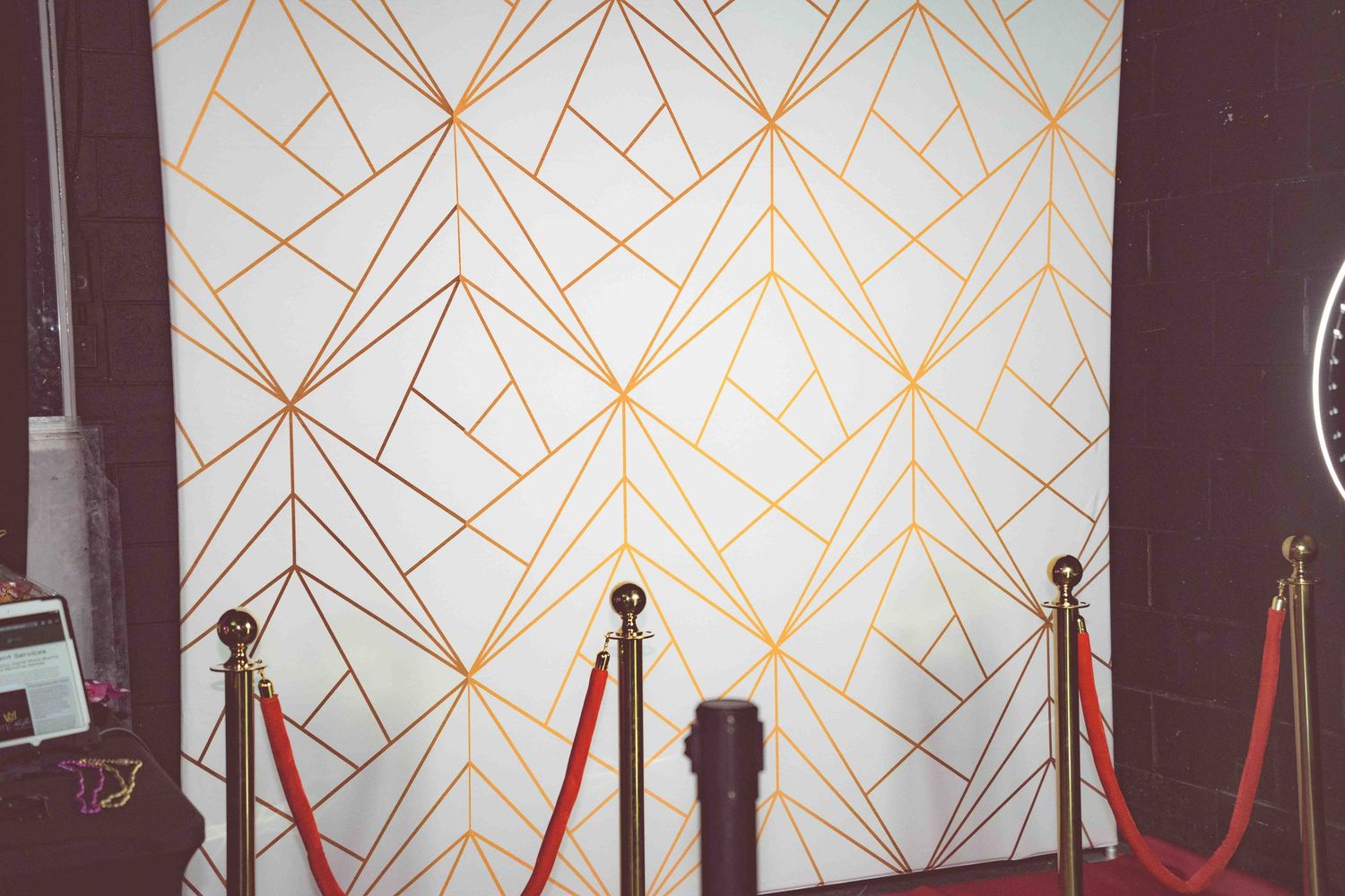 Art deco style wall with geometric gold patterns and velvet ropes.