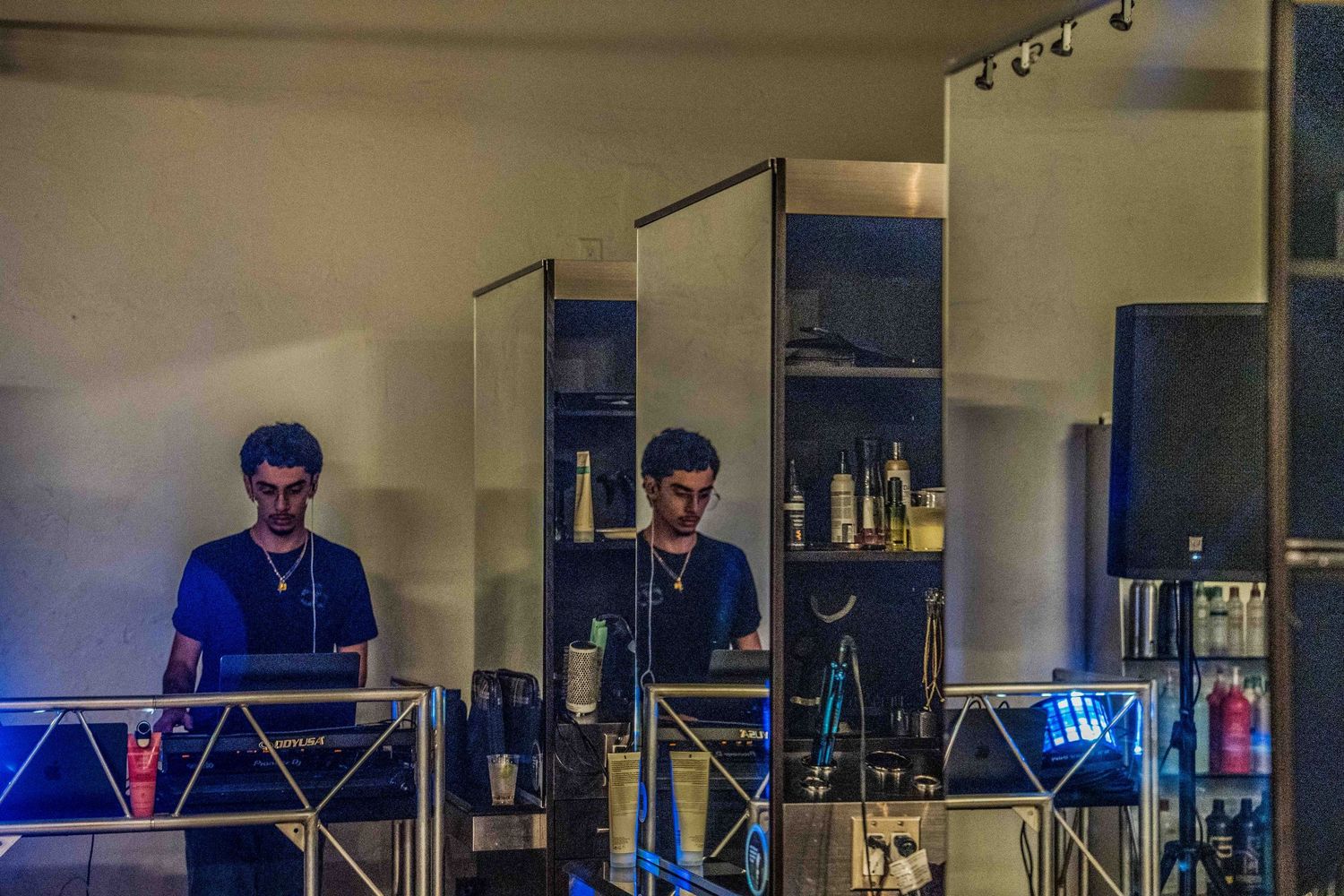 A DJ performing at a dimly lit venue with blue lights and mirror reflections.