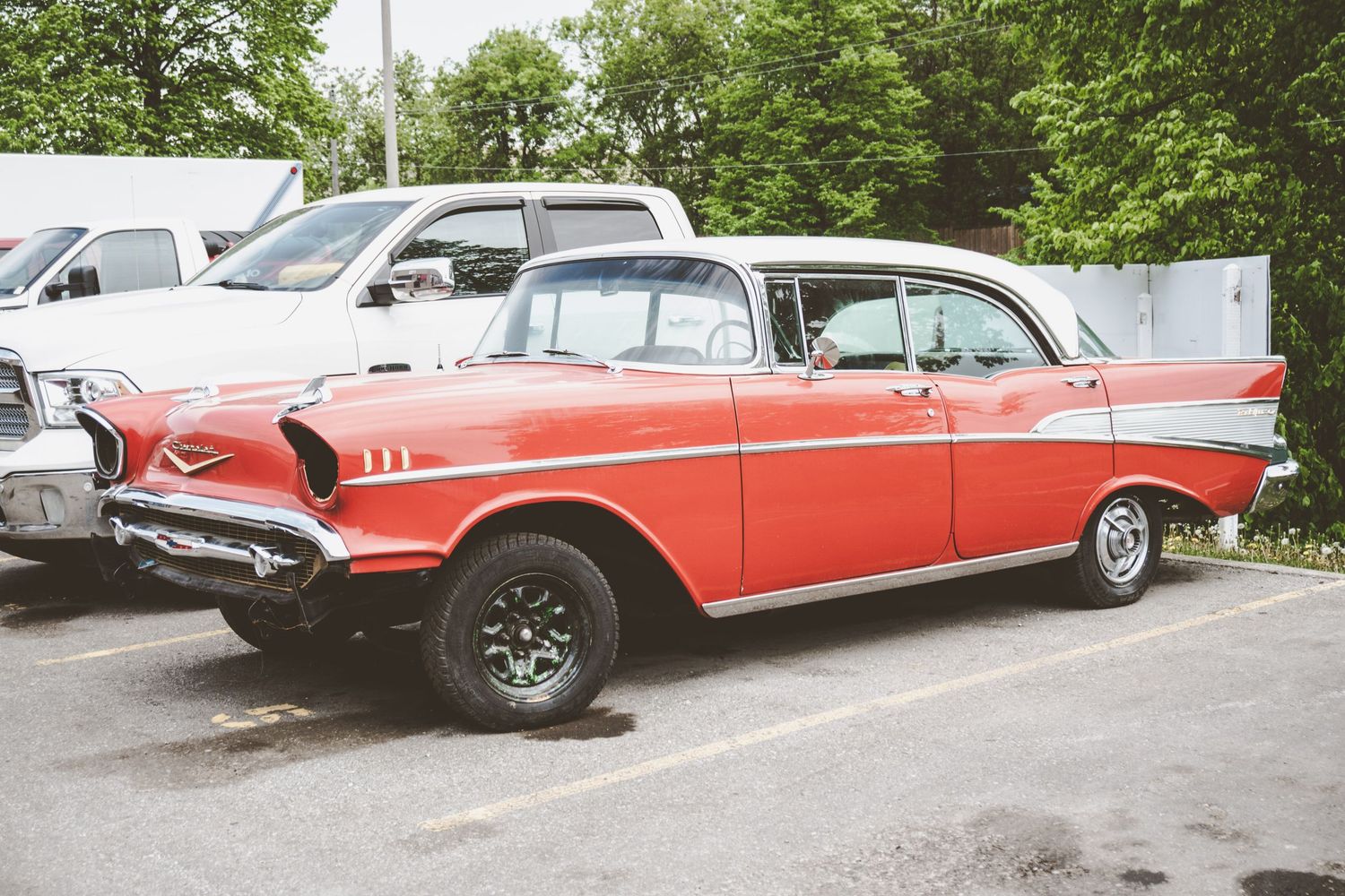Side profile of a vintage red and white classic car parked in a lot.