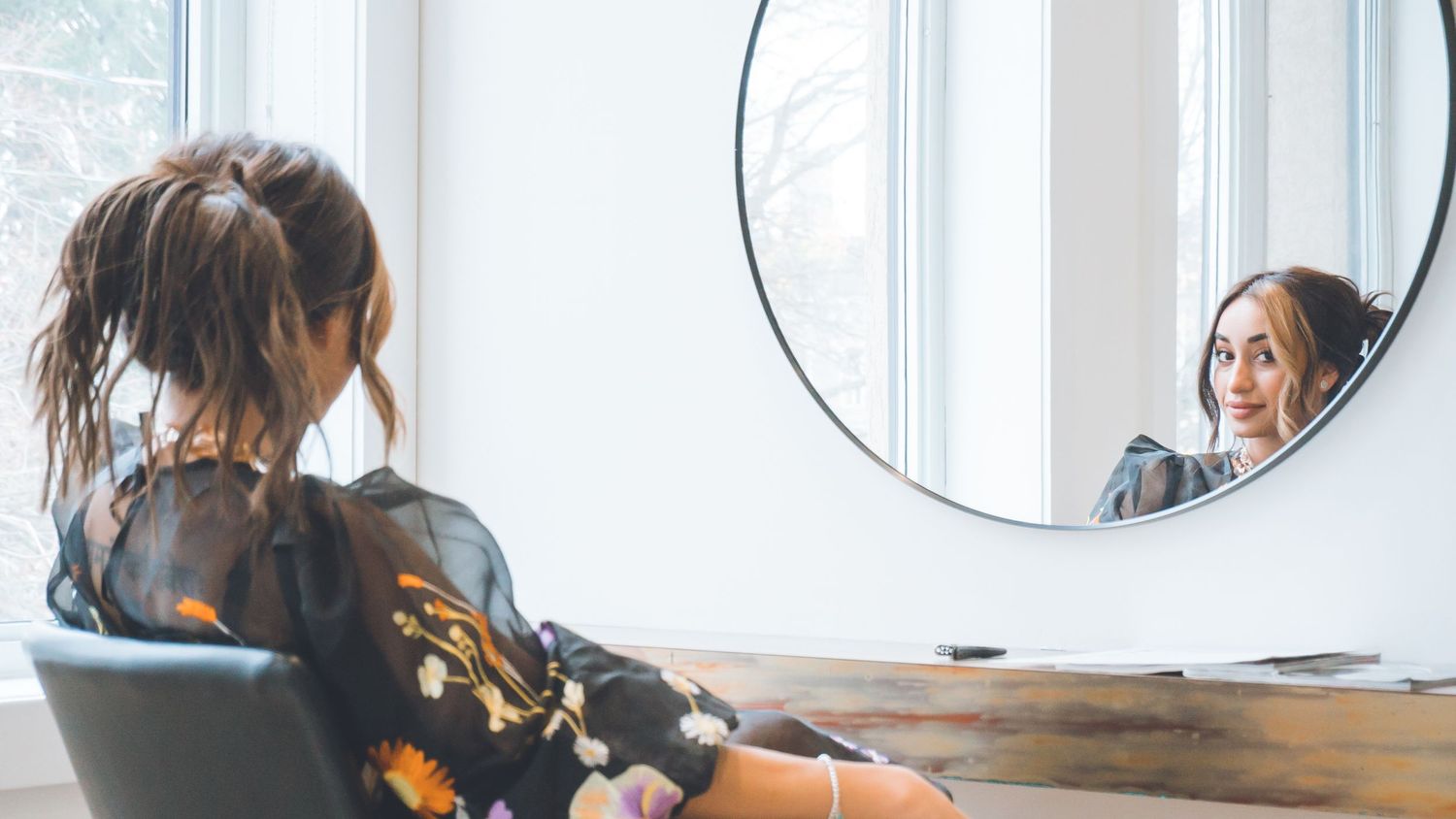 Row of vanity mirrors and chairs in a bright, modern salon or makeup studio.